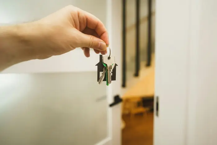 Main tendant un trousseau de clés devant une porte